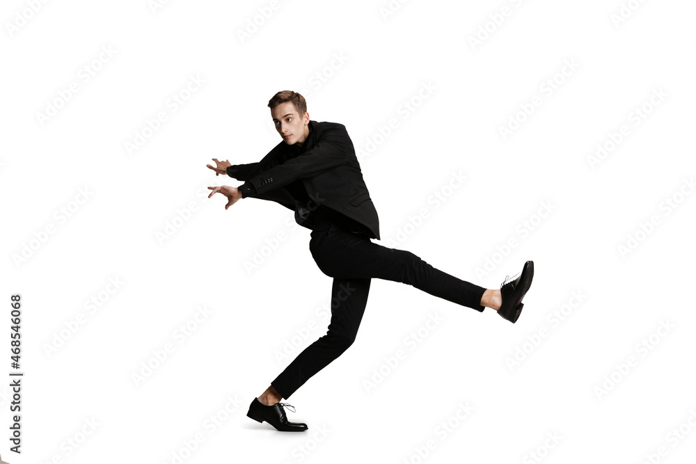 Young man in black business suit dancing isolated on white background. Art, motion, action, flexibility, inspiration concept.