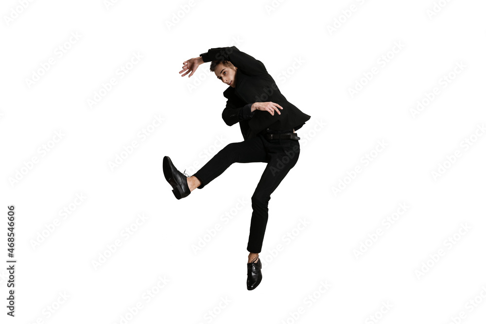 Dynamic portrait of young man in black business suit dancing isolated on white background. Art, motion, action