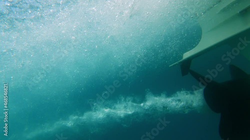 slow-motion close up of boat propeller spinning underwater producing air bubbles wake from engine photo