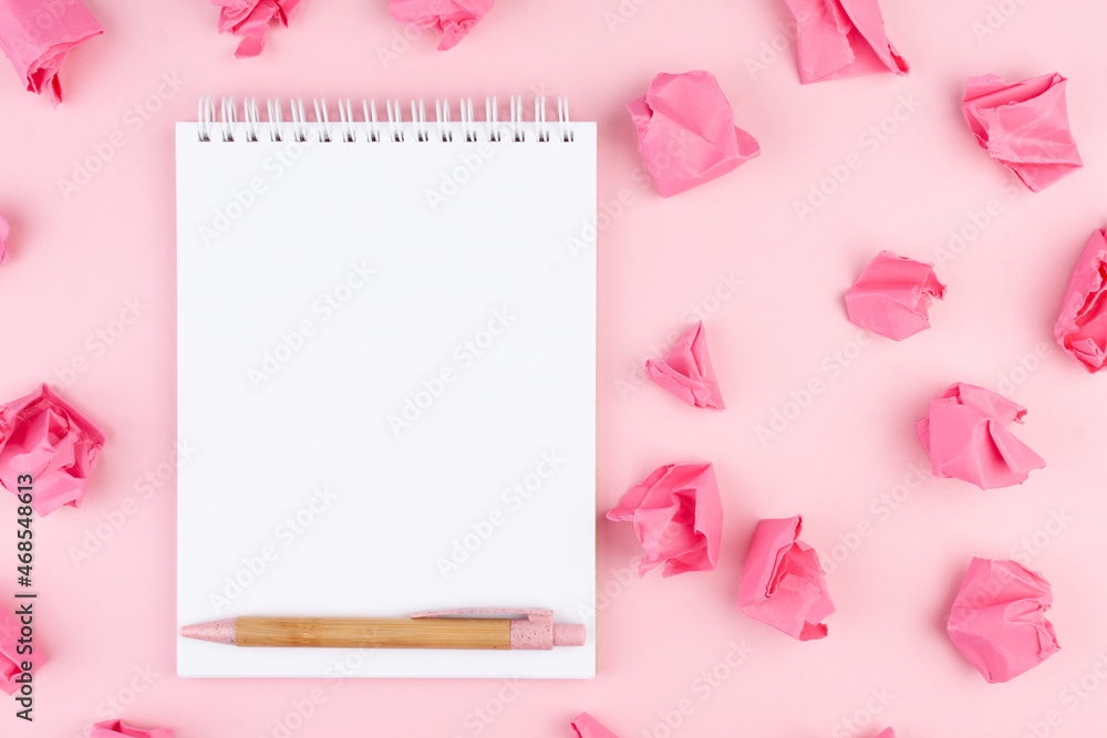 Notepad and pen on pink background in flat lay style. Planning concept for 2022.