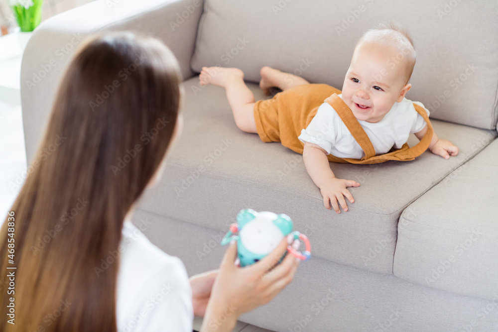 Photo of anonymous mother lady demonstrate showing excited curious kid new toy wear white t-shirt home indoors