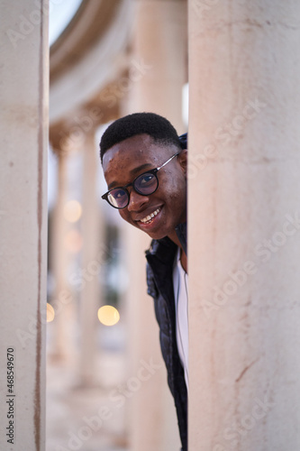 Cheerful black guy peeking from behind column