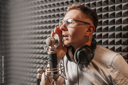 The vocalist sings in the studio in a microphone. Man in headphones writes a podcast, an audiobook. Artist, recording an album, working with the label. Announcer records a speech at a radio station photo