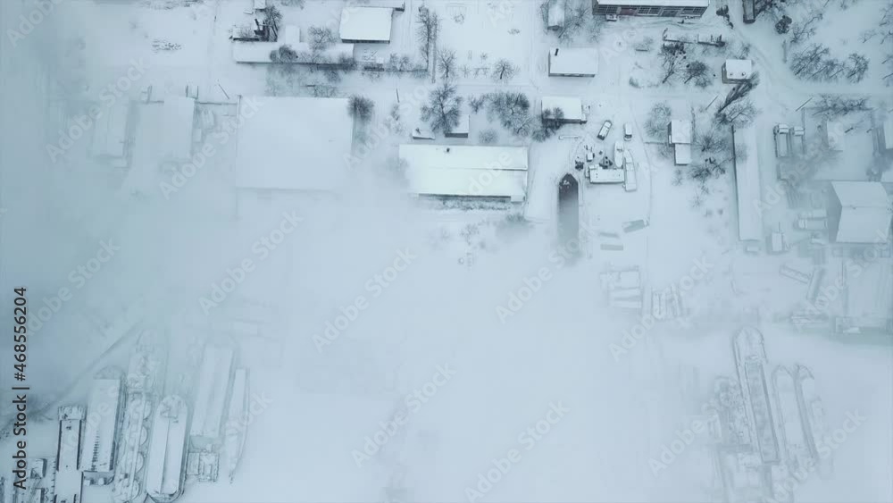 Flight over the industrial zone to the pipe of the heat power network with a loading dock with frozen water in ice. Plumes of smoke against the background of the city. Flight over the industrial zone to the pipe of the heat power network with a loading dock with frozen water in ice. Plumes of smoke against the background of the city.