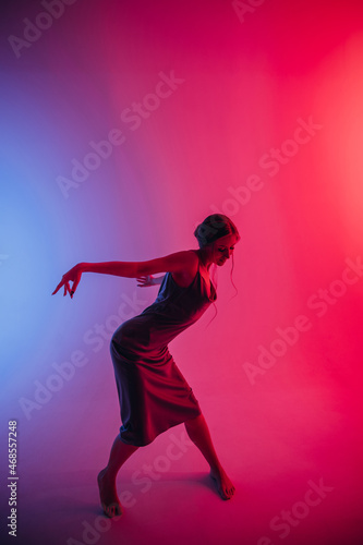 Fototapeta Naklejka Na Ścianę i Meble -  beautiful girl in a dress, blonde hair, dancing on a colored background with a pattern