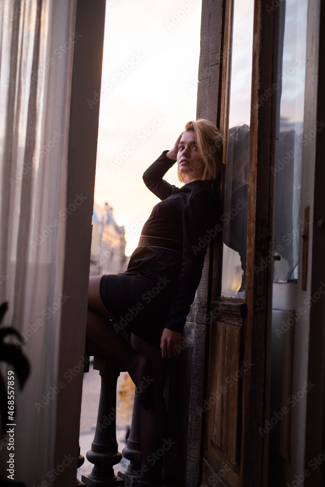 Beautiful young woman near the window on sunset. City view Beautiful young woman near the window on sunset. City view