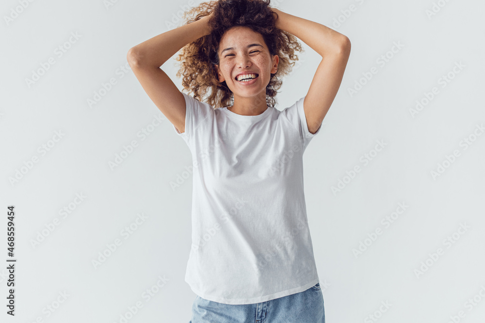 Smiling woman with lush curly hair in white blank t-shirt on a white background. Mock-up. Smiling woman with lush curly hair in white blank t-shirt on a white background. Mock-up.