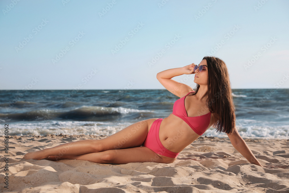 Beautiful young woman with attractive body posing on sandy beach Beautiful young woman with attractive body posing on sandy beach