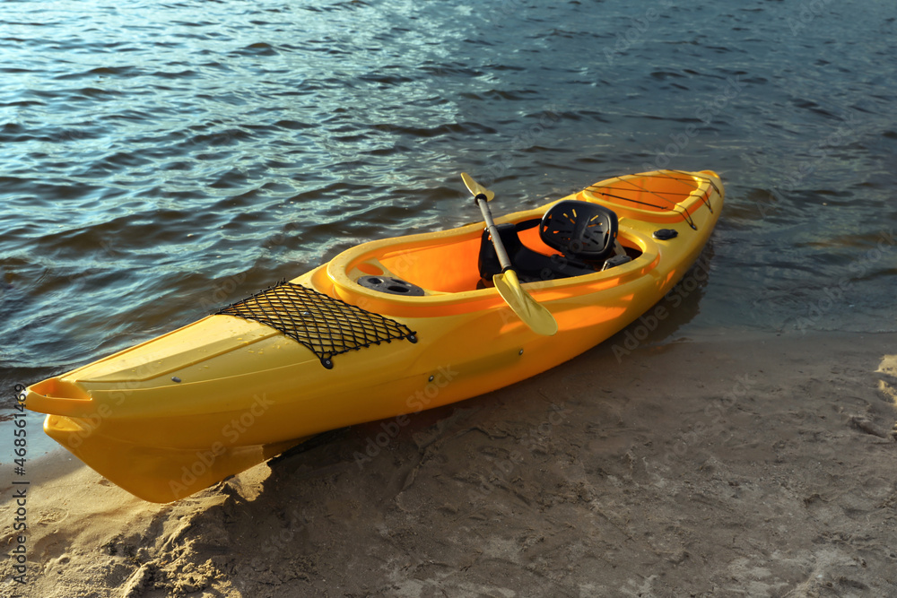 Beautiful modern yellow kayak with paddle on beach Beautiful modern yellow kayak with paddle on beach