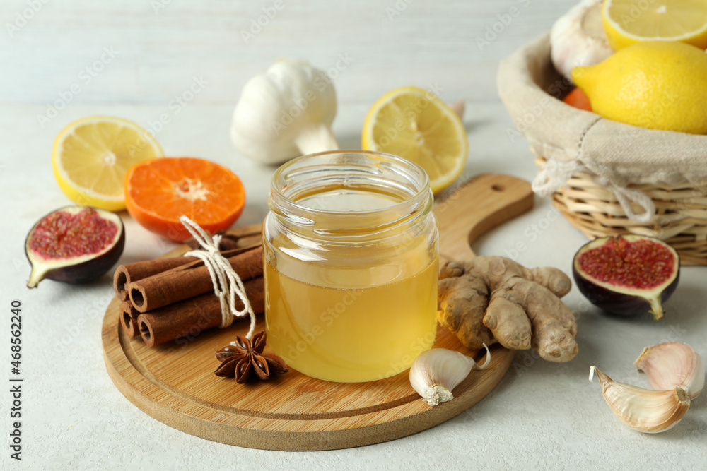 Concept of treatment colds with honey and garlic on white textured background Concept of treatment colds with honey and garlic on white textured background
