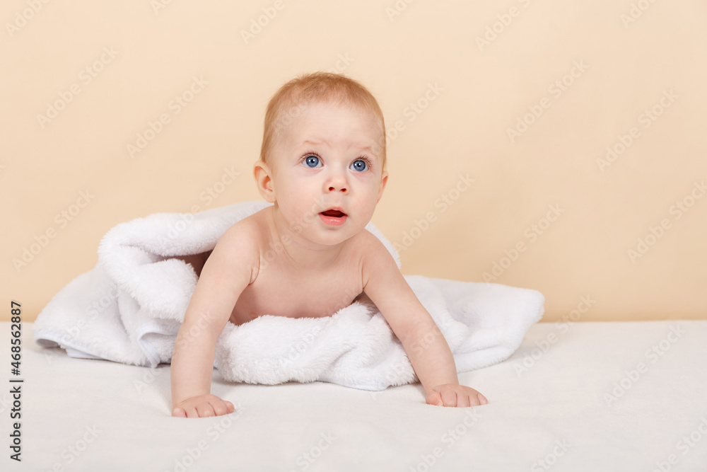 Adorable baby lie on white towel or blanket in bedroom. Close up portrait of little cute smiling baby boy at home. Happy childhood and healthcare concept. Childhood, infancy and baby care concept Adorable baby lie on white towel or blanket in bedroom. Close up portrait of little cute smiling baby boy at home. Happy childhood and healthcare concept. Childhood, infancy and baby care concept