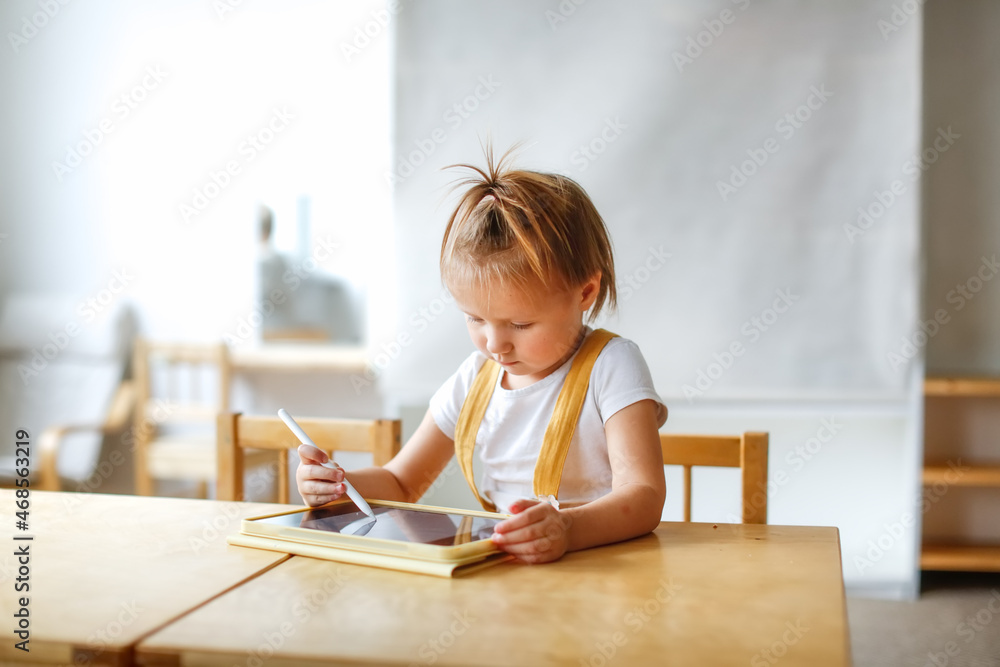 Funny cute baby girl toddler with tablet, child and gadget. Early development and drawing on the screen, the child plays and learns on the tablet Funny cute baby girl toddler with tablet, child and gadget. Early development and drawing on the screen, the child plays and learns on the tablet