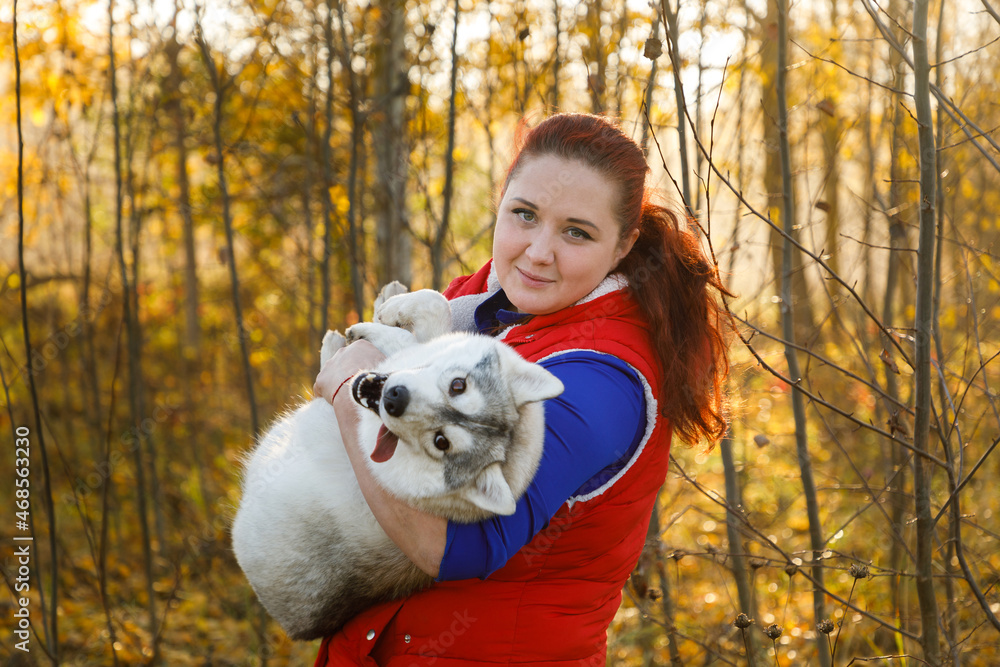 The dog breeder is hugging with her husky dog in autumn forest The dog breeder is hugging with her husky dog in autumn forest