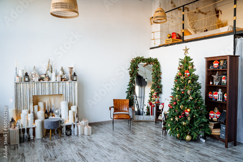 Interior shot. Two-storey room with fireplace  decorated Christmas tree  preparations for the new year Modern apartment. Red staff