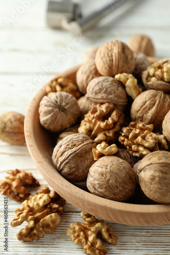Nutcracker and bowl of walnuts on white wooden background