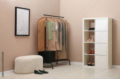 Photos Garment bags with clothes hanging on rack in room