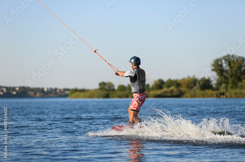 Teenage boy wakeboarding on river. Extreme water sport © New Africa