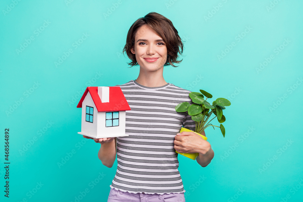 Photo of young attractive girl happy positive smile home flower plant move isolated over teal color background Photo of young attractive girl happy positive smile home flower plant move isolated over teal color background