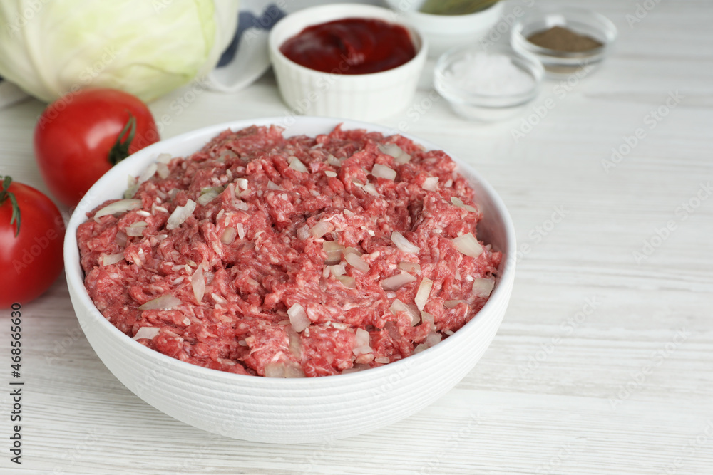 Meat filling in bowl and other ingredients for stuffed cabbage rolls on white wooden table Meat filling in bowl and other ingredients for stuffed cabbage rolls on white wooden table