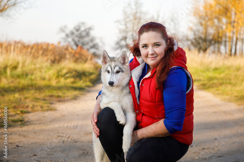 Murais de parede The dog breeder is hugging with her husky dog in autumn forest