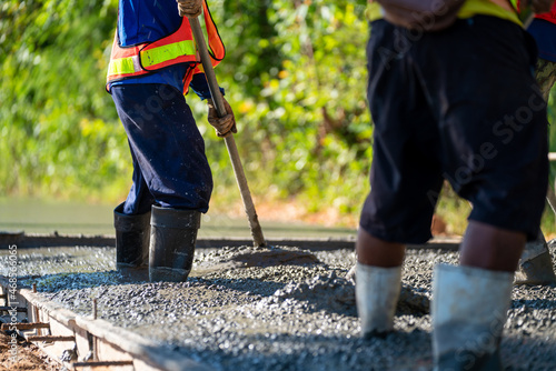 Pouring wet concrete while paving a driveway at road construction site