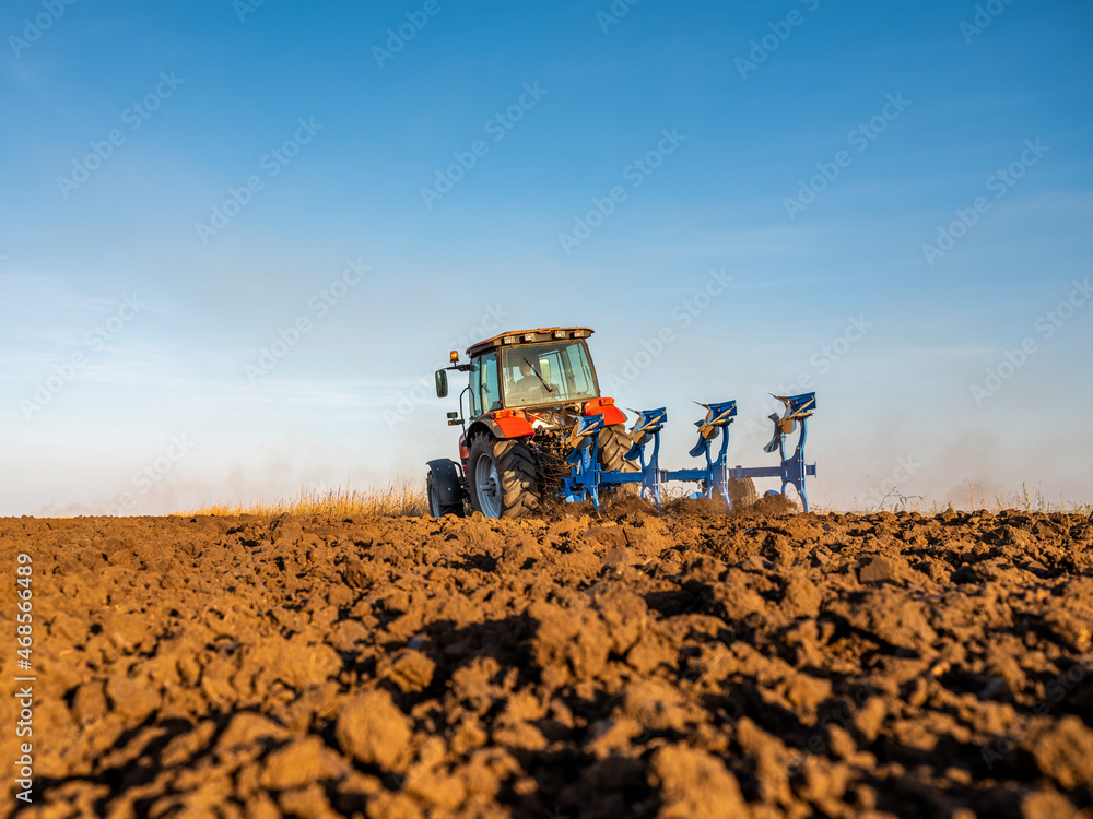 Fototapeta premium Farmer in tractor plowing preparing stubble field cultivating for seeding crops.