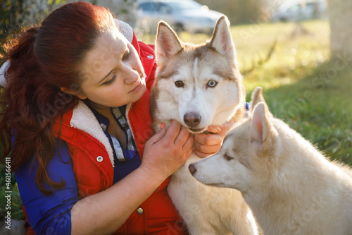 Fotografie, Obraz The dog breeder is hugging with her husky dogs outdoors