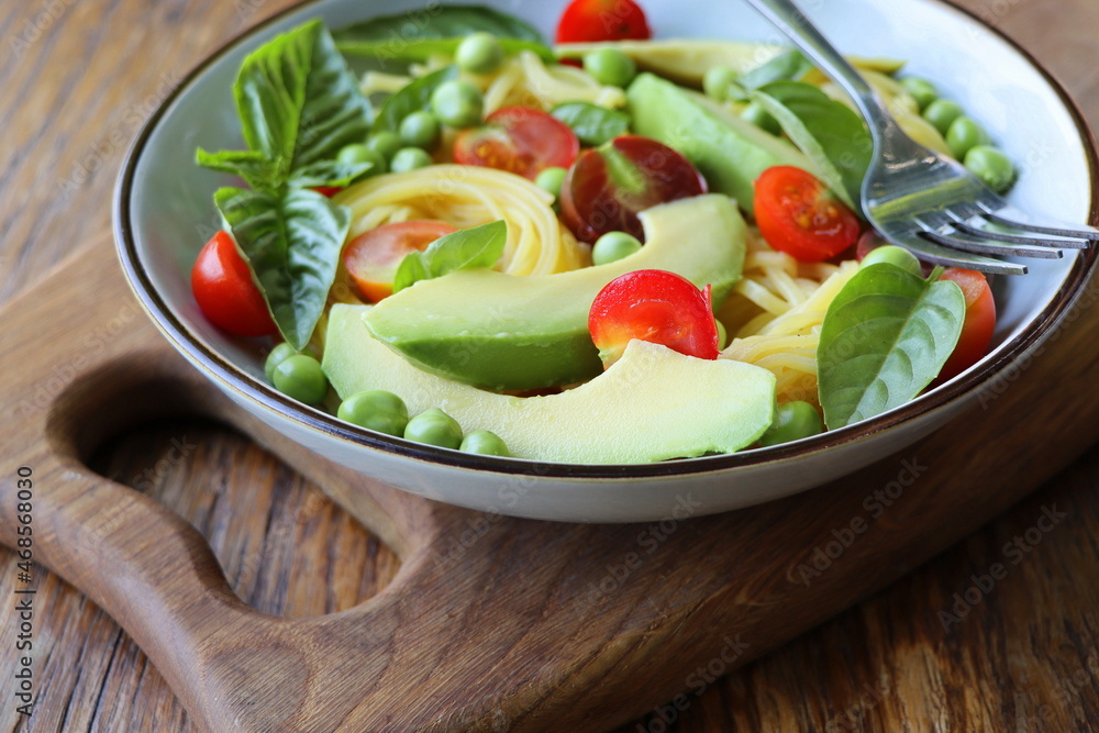 Pasta salad with green peas, avocado, cherry tomatoes and basil on rustic wooden background. Top view Pasta salad with green peas, avocado, cherry tomatoes and basil on rustic wooden background. Top view