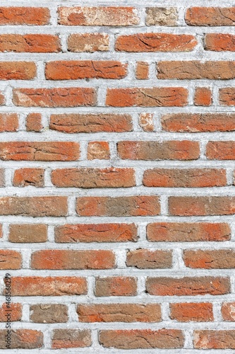 A texture portrait of a red brick masonry wall with cement. The stones are square or rectangular and are of different sizes.