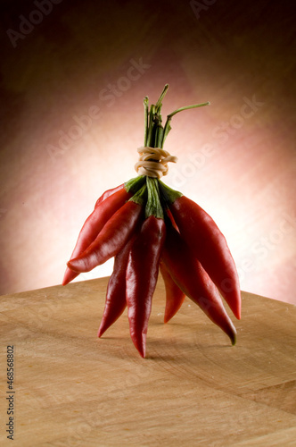 Bunch of red chilli peppers sitting on a timber bench