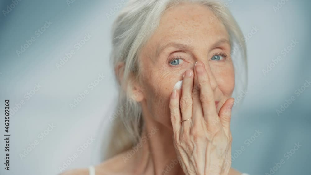 Portrait of Beautiful Senior Woman Gently Applying Face Cream. Elderly Lady Makes Her Skin Soft, Smooth, Wrinkle Free with Natural anti-aging Cosmetics. Product for Beauty Skincare, Makeup Portrait of Beautiful Senior Woman Gently Applying Face Cream. Elderly Lady Makes Her Skin Soft, Smooth, Wrinkle Free with Natural anti-aging Cosmetics. Product for Beauty Skincare, Makeup