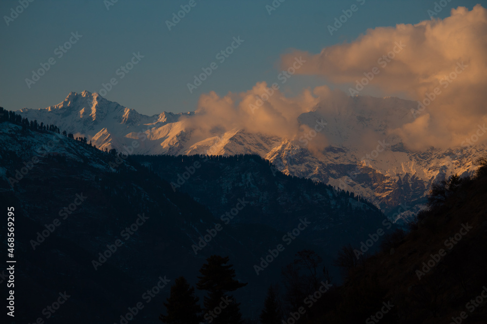 Orange clouds above the snow covered mountain peak during sunset in winter season at Manali in Himachal Pradesh, India