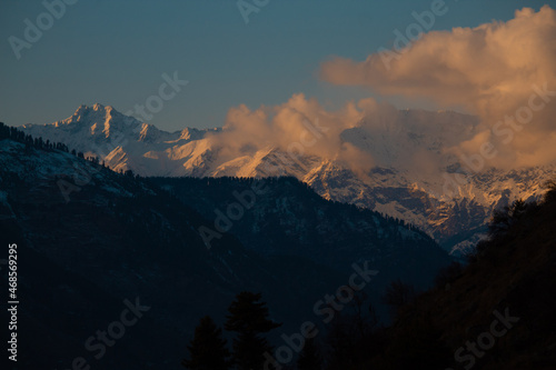 Orange clouds above the snow covered mountain peak during sunset in winter season at Manali in Himachal Pradesh, India © Shiv Mer