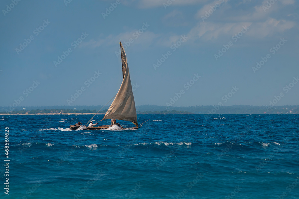 Naklejka premium Afrikan fishing sailboat Ngalawa goes on the deep blue waves near Mnemba island, Tanzania
