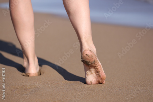 Female bare feet walking along seaside closeup