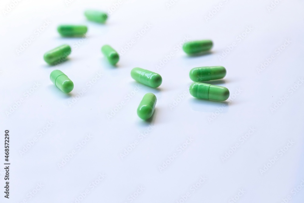 green pills on white background. Selective focus, blurred background