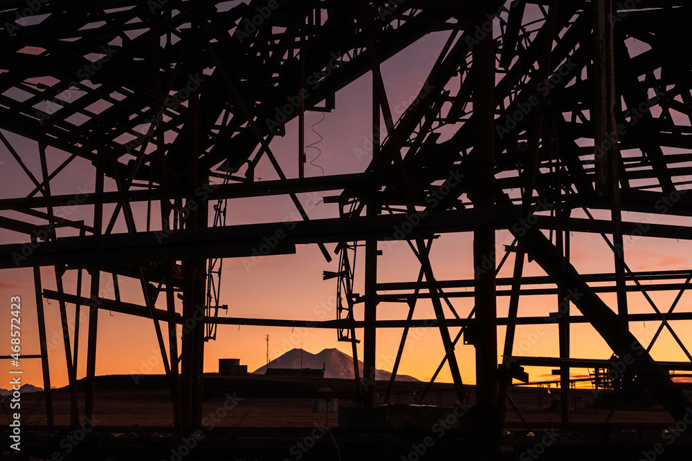 Urban night landscape, metal structures in the foreground. In the background is Mount Edbrus in the setting sun.