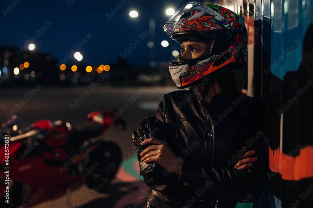 Woman biker in the helmet stay near his sportbike Woman biker in the helmet stay near his sportbike