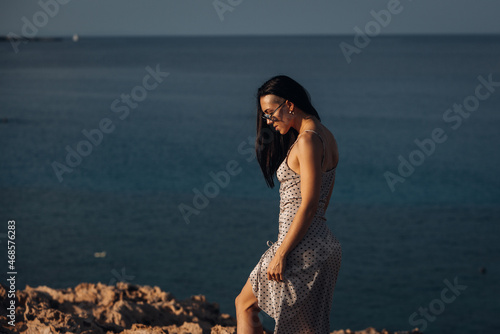 Beautiful young woman on the top of rock near ocean