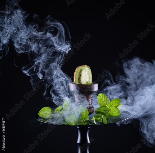 fruit hookah with tobacco, kiwi, mint and smoke on black background