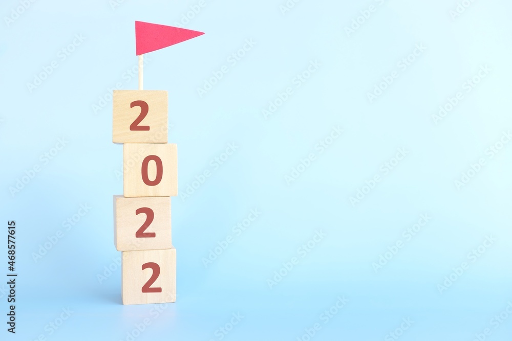 Year 2022 finish line, achievement, conclusion, review, summary and finishing annual report concept. Building blocks with 2022 number and red flag in blue background.