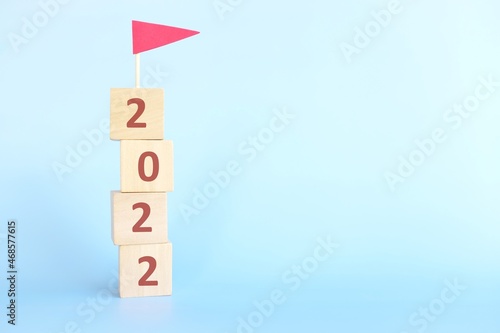 Year 2022 finish line, achievement, conclusion, review, summary and finishing annual report concept. Building blocks with 2022 number and red flag in blue background. photo
