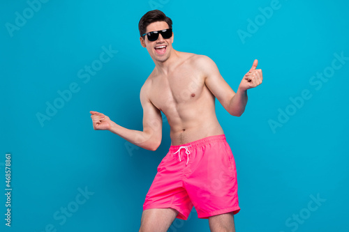 Photo of attractive funky young man naked torso dark eyewear dancing smiling isolated blue color background
