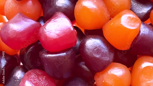 Close-up texture of red, orange and purple multivitamin gummies on white background. Healthy lifestyle concept