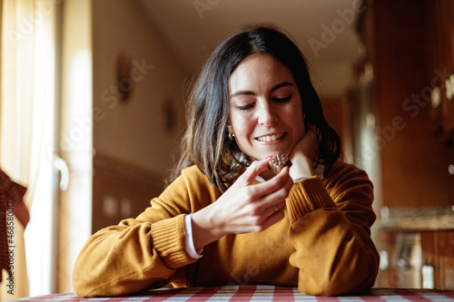 Beautiful young woman eating chocolate in candid kitchen