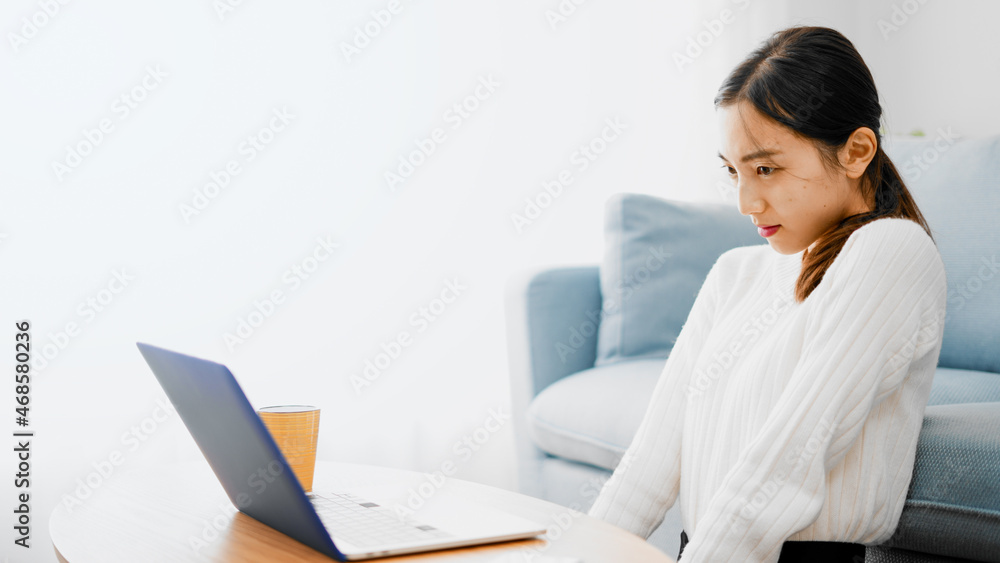ソファーでノートパソコンを使う若い女性 ソファーでノートパソコンを使う若い女性