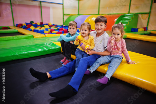 Kids playing in indoor play center and sitting on a trampoline. Large family with four children.