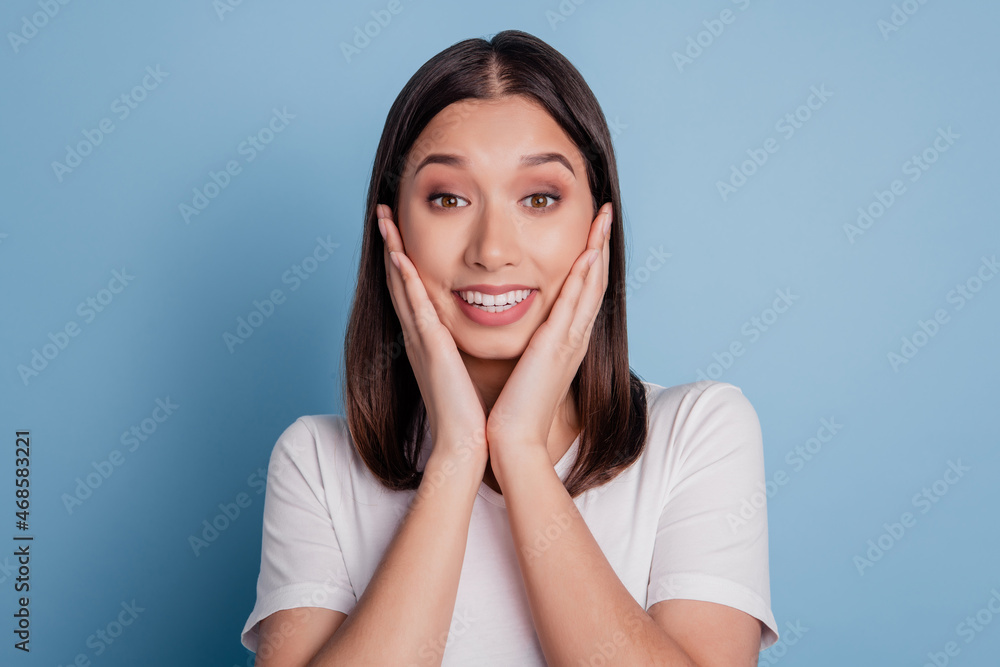 Photo of stylish casual amazed funky lady arms cheek look camera toothy beaming smile on blue background Photo of stylish casual amazed funky lady arms cheek look camera toothy beaming smile on blue background