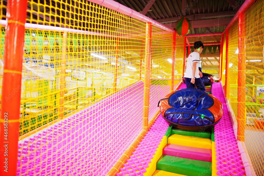 Fototapeta premium Happy two brothers in tubing donuts enjoying slides in fun children center.