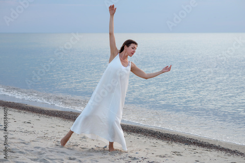 Fotografia Woman dancing in white dress near the sea